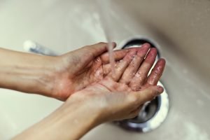Two hands are shown under a running faucet.